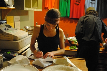 Women writing on a piece of paper behind a counter